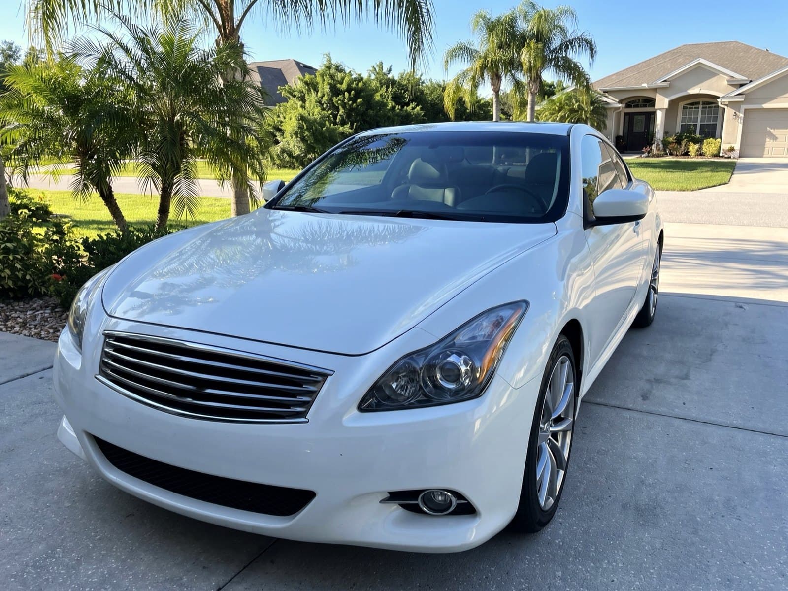 A white coupe in a driveway lined with palms in Bartow, FL, after a Bang AutoGlass mobile glass job