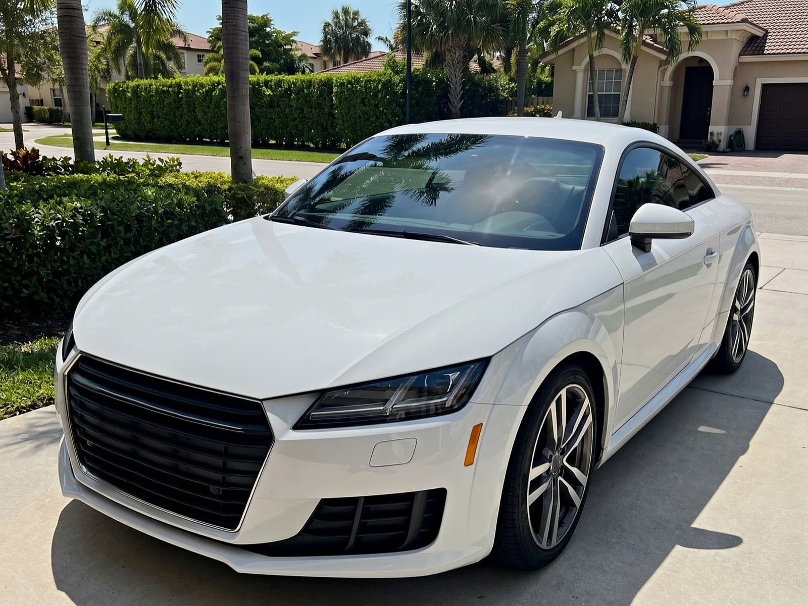 A white coupe in a driveway in Doral, FL, after a Bang AutoGlass mobile glass job