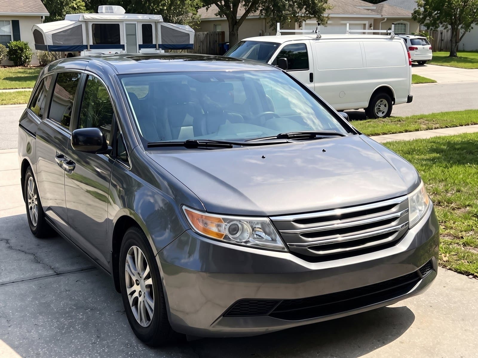 A grey minivan in a driveway in Longwood, FL, after a Bang AutoGlass mobile glass job