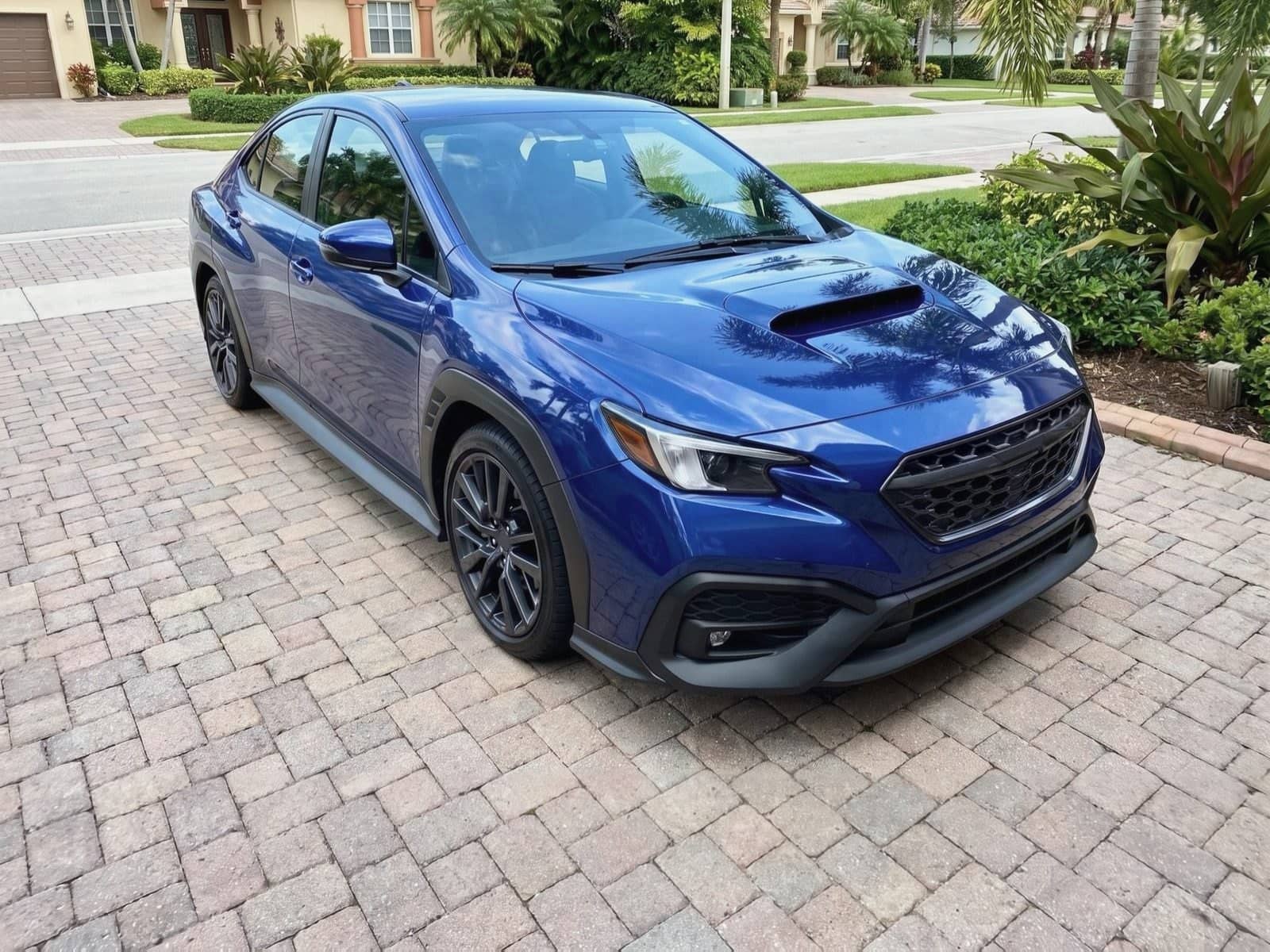 Blue sports sedan on brick pavers in Fort Lauderdale, Florida, after a Bang AutoGlass mobile glass job