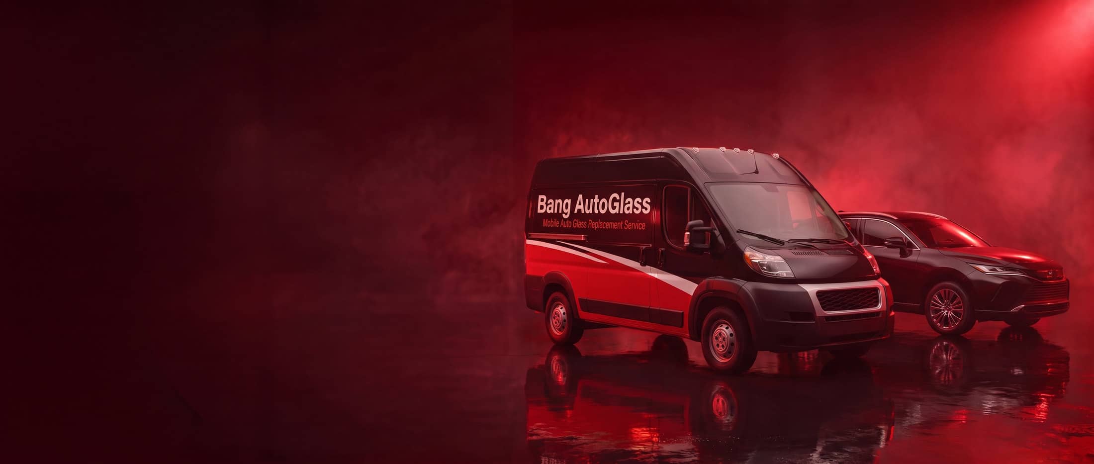 A black-and-red van marked Bang AutoGlass beside a dark SUV under red studio lighting