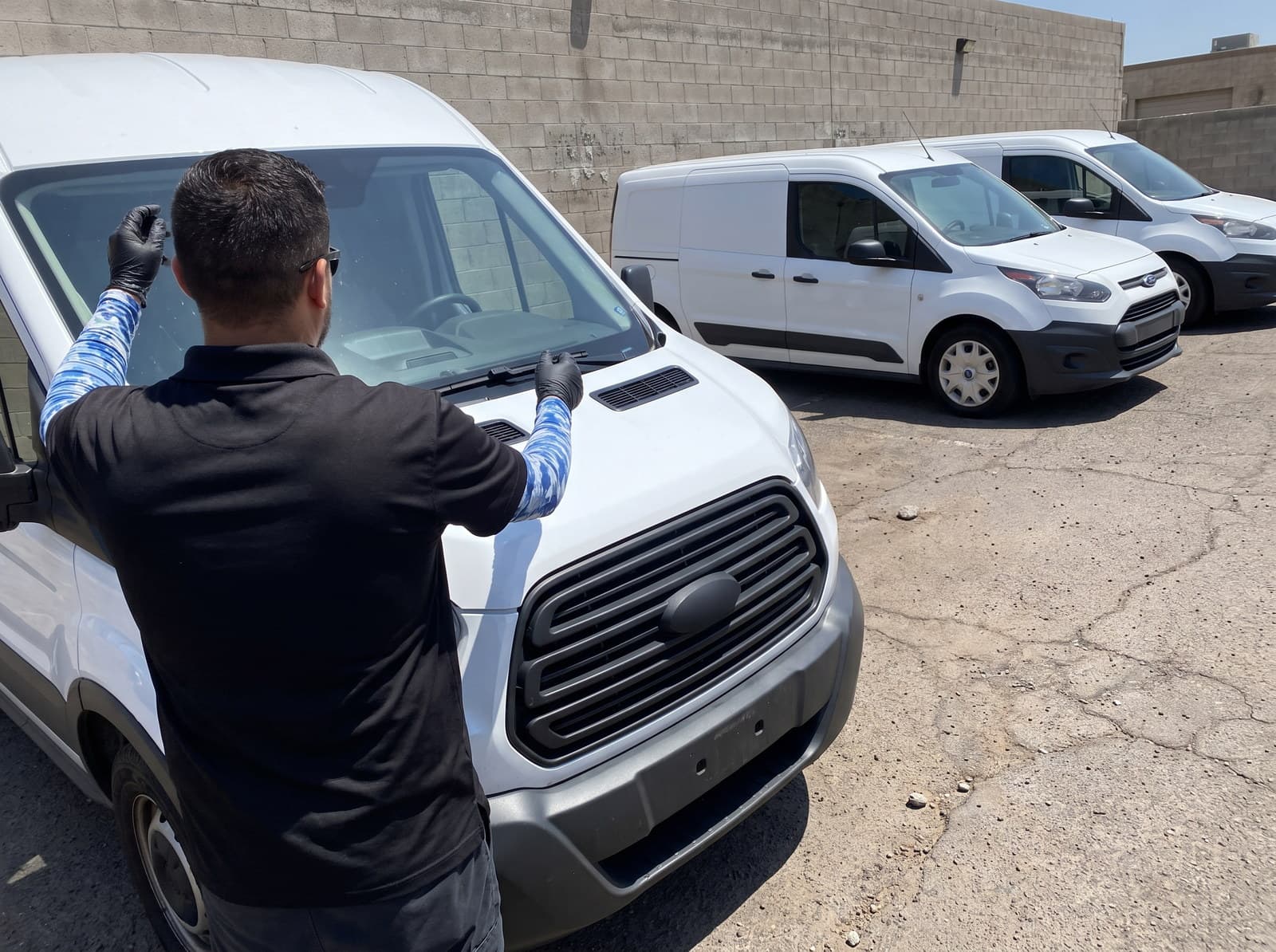 Setting a windshield into a white work van in a fleet yard