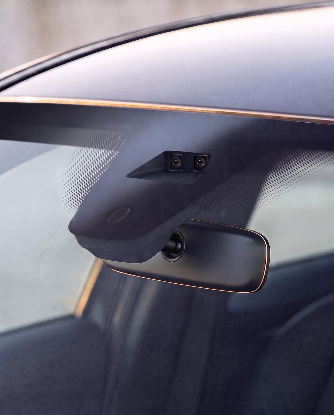 A forward camera housing at the top of a windshield, behind the rear-view mirror.