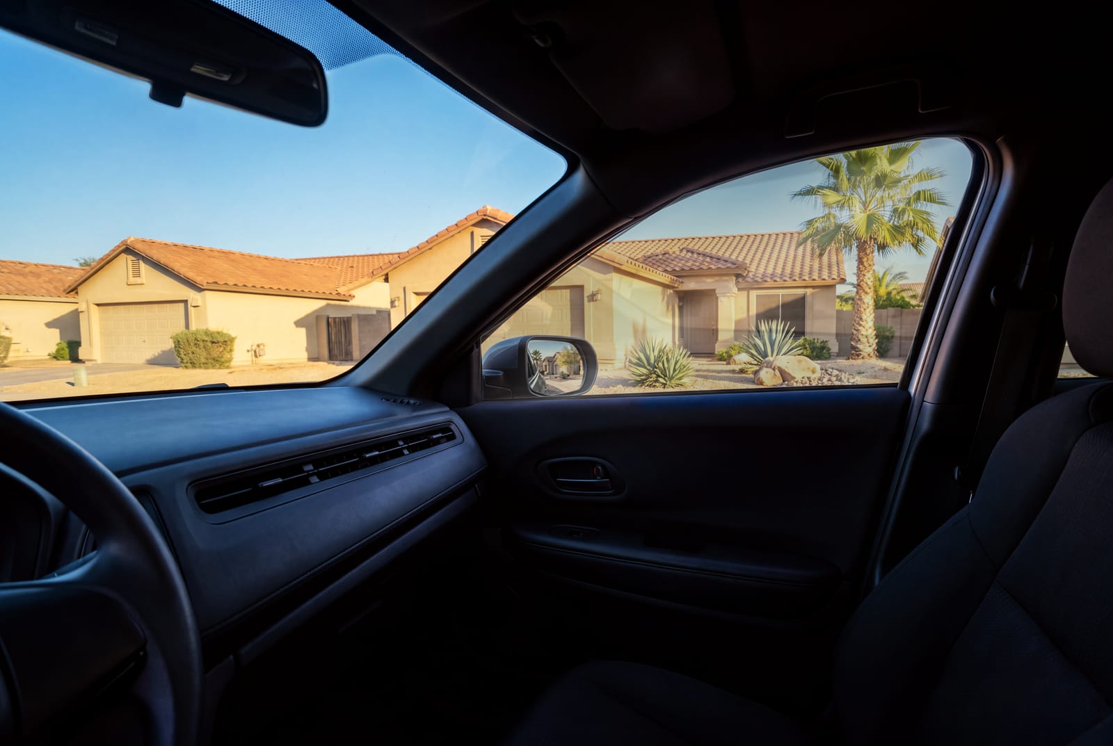 The same view through a new passenger door window, closed and clear, with the same stucco homes outside.